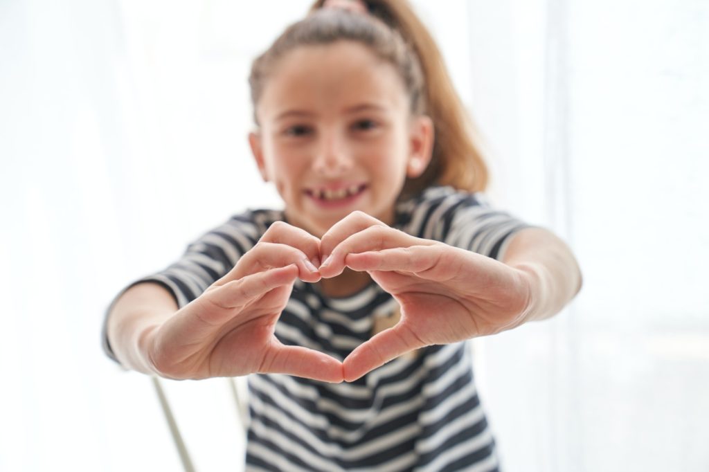 Girl showing heart gesture with hands